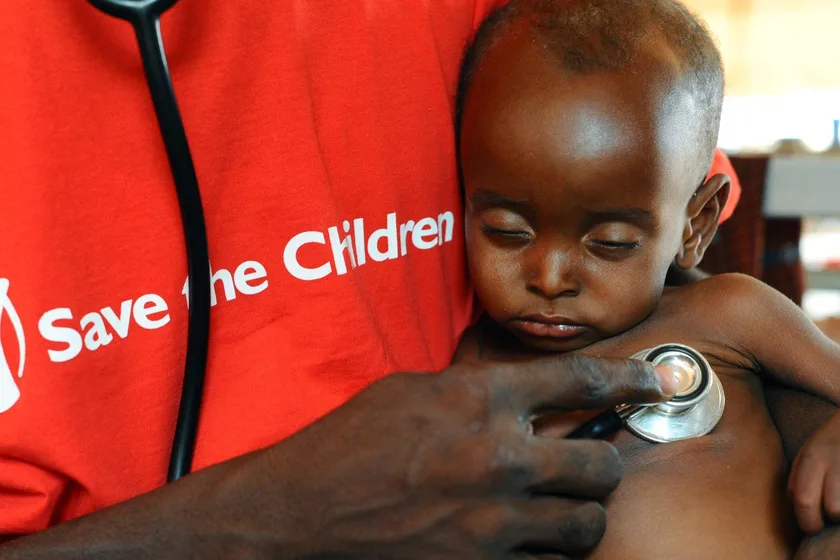 A Save the Children health worker listening to a small child’s chest with a stethoscope
